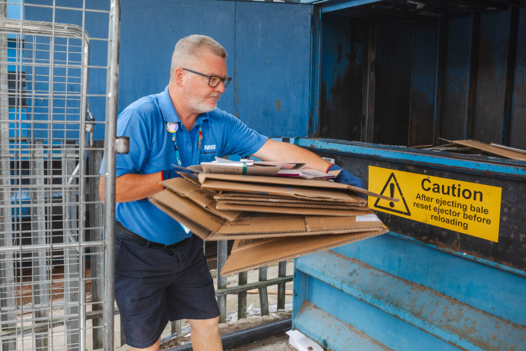 Porter putting used cardboard into a baling machine